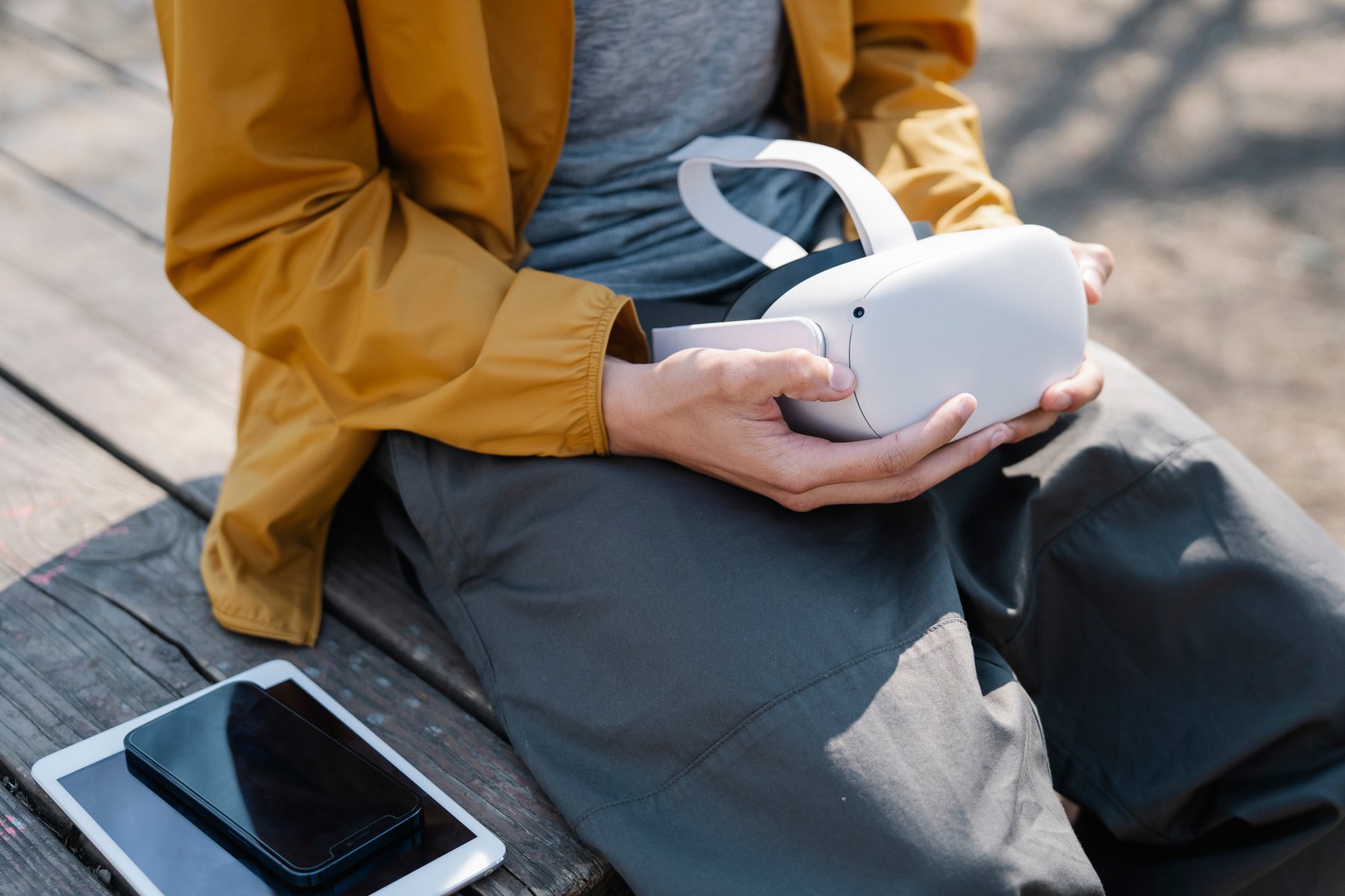 Crop person sitting on bench with contemporary devices